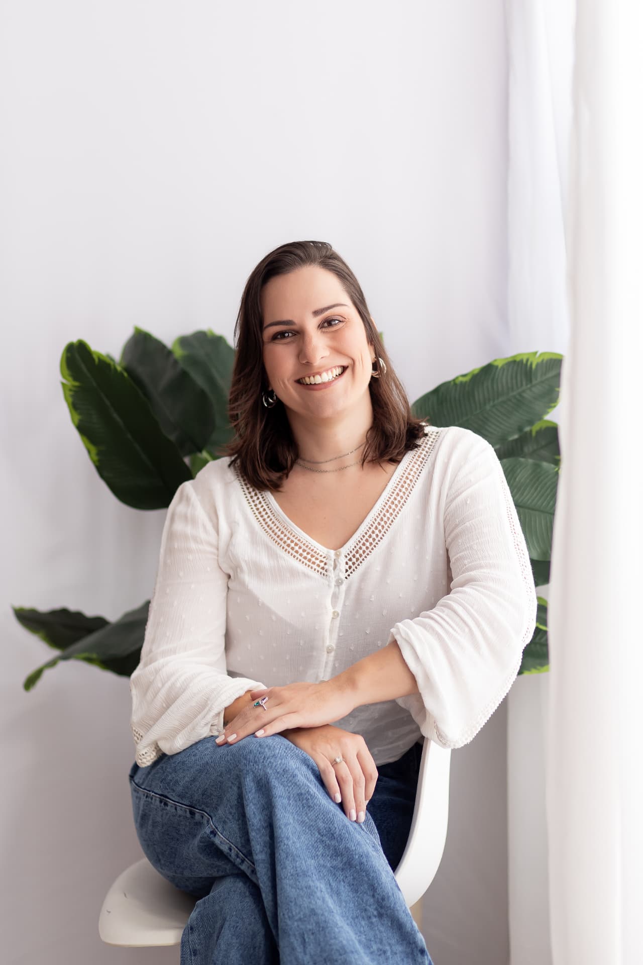 Mariana Lanza Guarnieri sentada, sorrindo, com plantas ao fundo